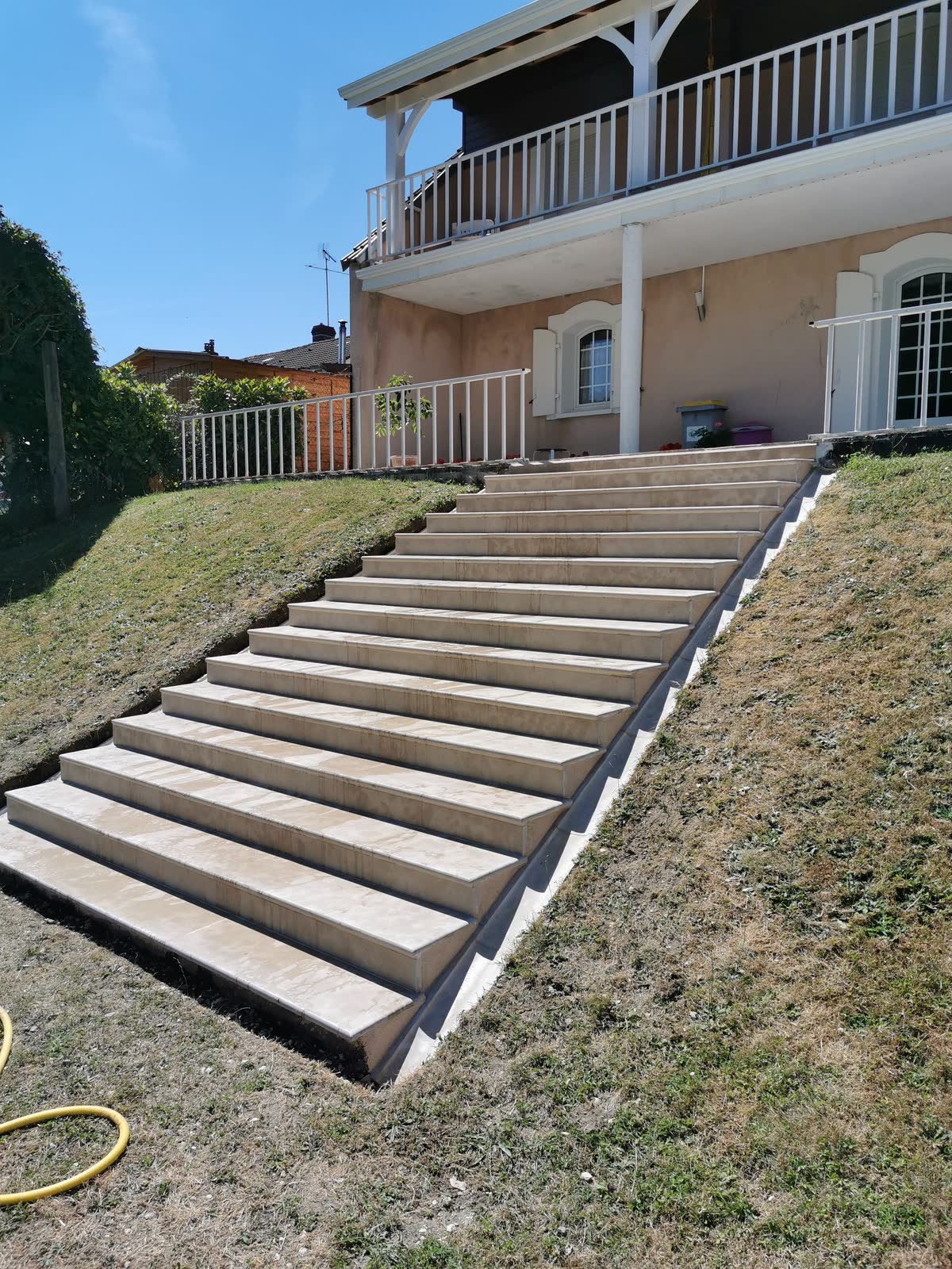 Grand escalier extérieur en pierre massive menant à une maison à balcon